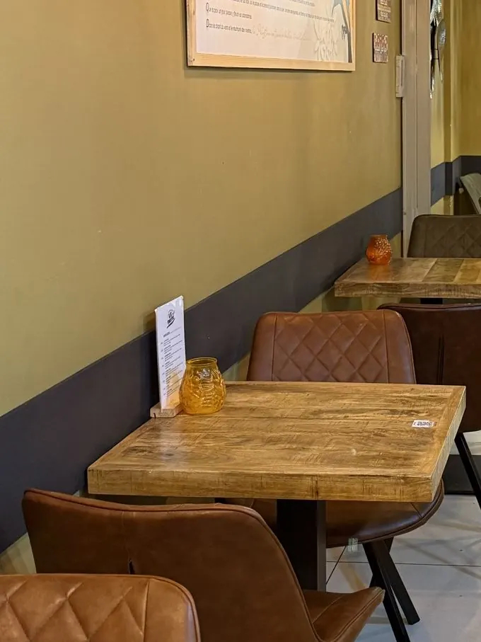 La salle de My Falafel a des murs kaki coupés d’un bandeau anthracite, des tables en bois et une carte papier posée sur un chevalet.