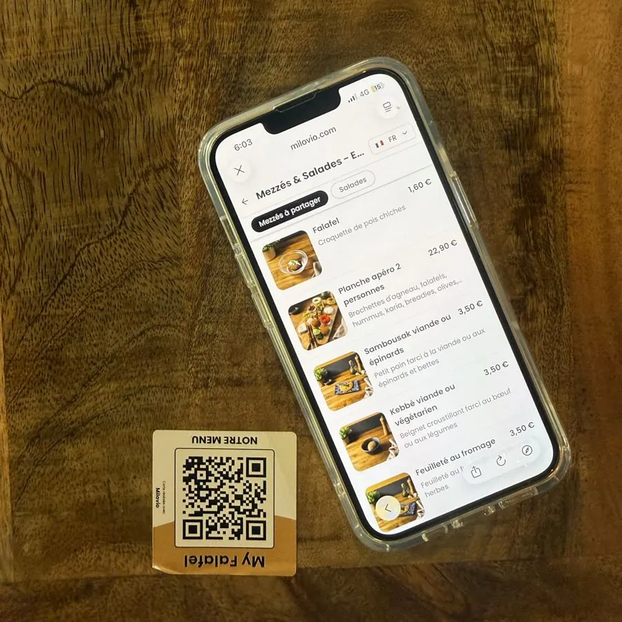 Un téléphone est posé à côté de l’Autocollant QR, sur une table de My Falafel vue du dessus.